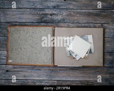 Vintage-Fotoalbum auf dunklem Holztisch. Das Thema Familienwerte. Die Aussicht von oben. Flache Lagen. Antikes Album mit alten Fotos Stockfoto