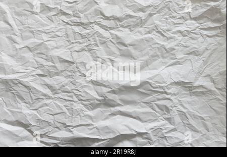 Faltige weiße Papierstruktur. Abstrakter Hintergrund in hoher Auflösung. Zufällige Falten und Wellen. Vollbild-Hintergrundbild. Stockfoto