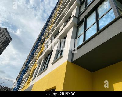 Blick von unten nach oben auf ein hohes großes Haus eines neuen Gebäudes vor einem Hintergrund mit blauem Himmel. Stockfoto