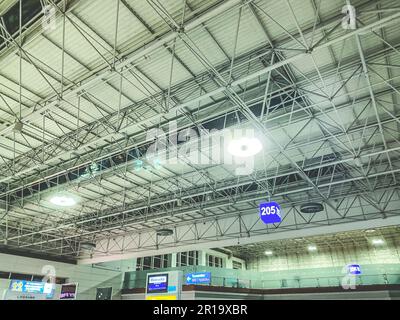 Decke im Technikraum. An der Spitze befinden sich Metallstrukturen mit Lampen und Warteschlangennummern. Lager mit Haushaltswaren. Stockfoto