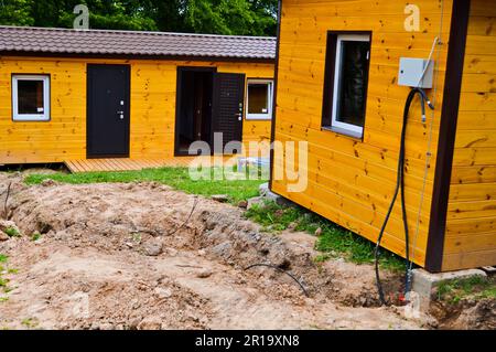 Bau eines kleinen gelben Holzrahmens vorgefertigtes Öko-Haus aus modularen, schnell wachsenden Vorstadthäusern, Gebäuden, Hütten. Industr Stockfoto