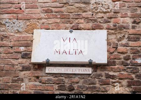 Siena, Italien - 7. April 2022: Traditionelles Marmorstraßenschild in der historischen Stadt Siena, Toskana, Italien. Über Malta. Stockfoto