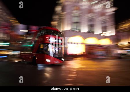 Ein roter Londoner Doppeldeckerbus, der im Stadtzentrum vorbeifährt und eine Langzeitbelichtungstechnik verwendet, um Bewegungsunschärfe zu erzeugen Stockfoto