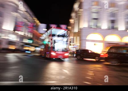 Ein roter Londoner Doppeldeckerbus, der im Stadtzentrum vorbeifährt und eine Langzeitbelichtungstechnik verwendet, um Bewegungsunschärfe zu erzeugen Stockfoto