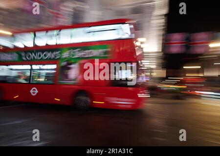 Ein roter Londoner Doppeldeckerbus, der im Stadtzentrum vorbeifährt und eine Langzeitbelichtungstechnik verwendet, um Bewegungsunschärfe zu erzeugen Stockfoto