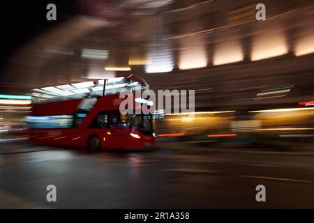 Ein roter Londoner Doppeldeckerbus, der im Stadtzentrum vorbeifährt und eine Langzeitbelichtungstechnik verwendet, um Bewegungsunschärfe zu erzeugen Stockfoto