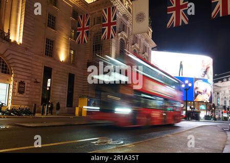 Ein roter Londoner Doppeldeckerbus, der im Stadtzentrum vorbeifährt und eine Langzeitbelichtungstechnik verwendet, um Bewegungsunschärfe zu erzeugen Stockfoto