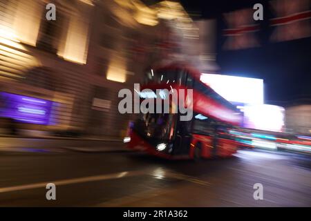 Ein roter Londoner Doppeldeckerbus, der im Stadtzentrum vorbeifährt und eine Langzeitbelichtungstechnik verwendet, um Bewegungsunschärfe zu erzeugen Stockfoto