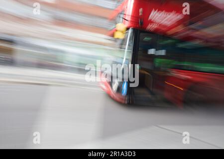 Ein roter Londoner Doppeldeckerbus, der im Stadtzentrum vorbeifährt und eine Langzeitbelichtungstechnik verwendet, um Bewegungsunschärfe zu erzeugen Stockfoto