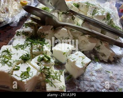 Roher Quark in einer Schüssel und Löffel auf einem weißen Tisch. Milchprodukte. Russischer Hüttenkäse und Serviette, Frühstückskonzept. Gesundes vegetarisches Essen, ein Stockfoto