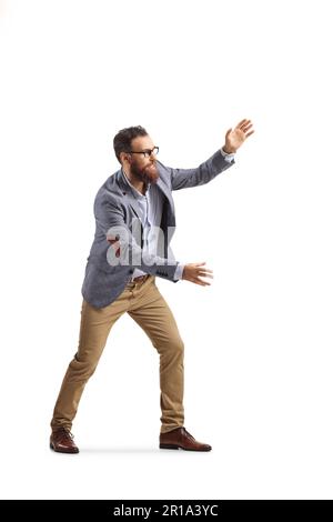 Die volle Länge eines fröhlichen bärtigen Mannes, der versucht, etwas isoliertes auf weißem Hintergrund zu fangen Stockfoto
