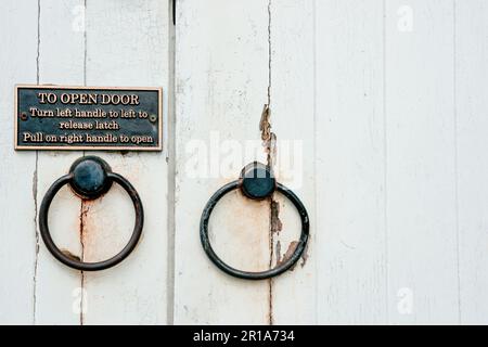 Kerikeri neuseeland - März 3 2011; Schild mit Anweisungen zum Öffnen der Tür auf weißer beschädigter Tür Stockfoto