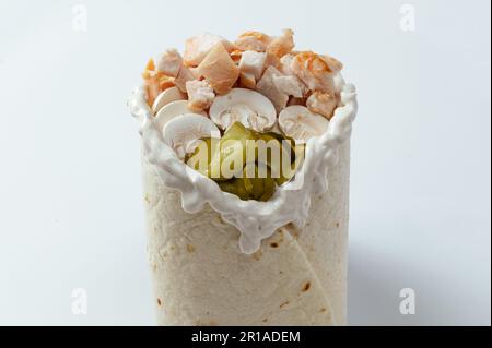 Hähnchen-Schawarma, verpackt in Pita-Brot und frischem, saftigen Salat und Sauce auf Holzbretterhintergrund Stockfoto