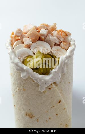 Hähnchen-Schawarma, verpackt in Pita-Brot und frischem, saftigen Salat und Sauce auf Holzbretterhintergrund Stockfoto