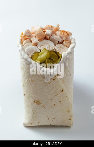 Hähnchen-Schawarma, verpackt in Pita-Brot und frischem, saftigen Salat und Sauce auf Holzbretterhintergrund Stockfoto