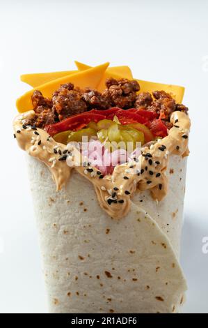 Hähnchen-Schawarma, verpackt in Pita-Brot und frischem, saftigen Salat und Sauce auf Holzbretterhintergrund Stockfoto