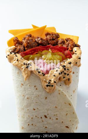 Hähnchen-Schawarma, verpackt in Pita-Brot und frischem, saftigen Salat und Sauce auf Holzbretterhintergrund Stockfoto