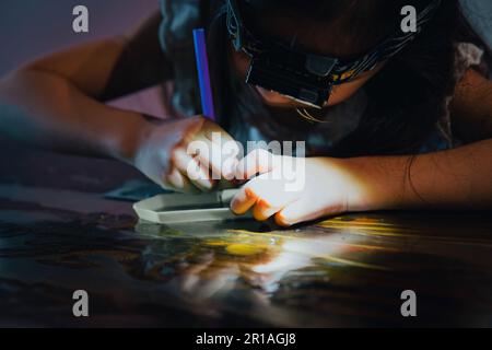 Ein junges Mädchen kreiert Kunstwerke mit eigenen Händen, indem es Juwelen kleben lässt. Stockfoto