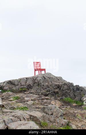 Roter Holzstuhl auf einem Stein. Abstrakte Landschaft in Island Stockfoto