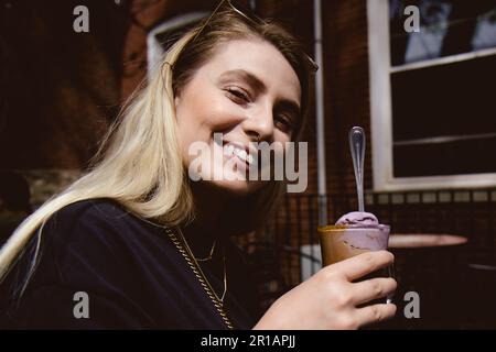 Lächelnde blonde Frau, die Kaffee auf der Terrasse im Freien trinkt Stockfoto