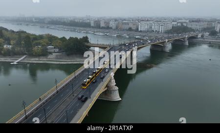 Aus der Vogelperspektive auf die Margaretenbrücke oder die Margit, die sich über der Donau und dem Ufer versteckten. Gelbe Straßenbahn über die Brücke Stockfoto
