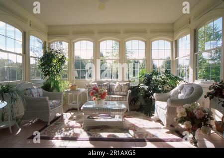 Sonnenzimmer voller Licht mit weißen Korbmöbeln und Pflanzen im Innenbereich, Missouri, USA Stockfoto