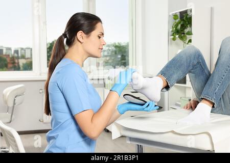 Schöne Orthopädin-Einlegesohle am Fuss des Patienten im Krankenhaus Stockfoto