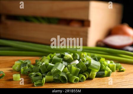 Gehackte grüne Frühlingszwiebel auf Holzbrett, Nahaufnahme Stockfoto