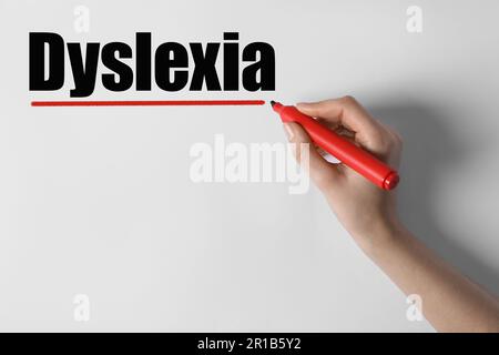 Frau schreibt Wort Dyslexie auf weißem Hintergrund, Nahaufnahme Stockfoto
