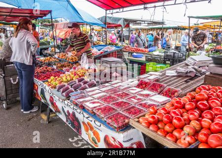 Junger Mann, der seine Produkte an eine Frau auf einem Bauernmarkt in Zapote, Costa Rica, verkauft. Stockfoto