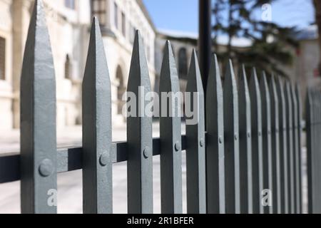 Ein zerklüfteter Metallzaun gegen ein altes Gebäude auf der Straße der Stadt Stockfoto