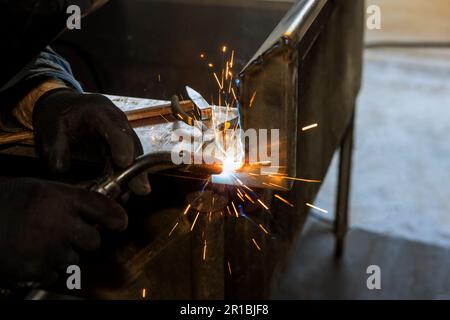 Ein erfahrener Arbeiter in der Schwerindustrie trägt Schutzmaske und Schweißstahl in der Fabrik mit Argon Stockfoto