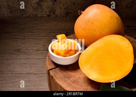 Mango- und Mangoscheiben mit Würfeln auf schwarzem Hintergrund. Thailändische Mangos. Thailändische Früchte. Text kopieren. Leerzeichen kopieren. Horizontale Mangofrüchte. Stockfoto