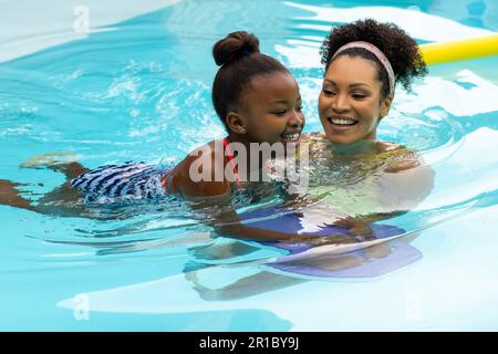 Glückliche afroamerikanische Mutter, die ihrer Tochter das Schwimmen im Schwimmbad beibrachte Stockfoto