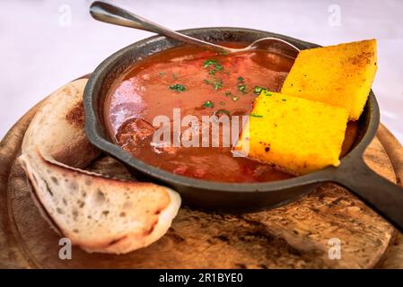 Gulyas, traditionelles ungarisches Gericht, herzhafter Eintopf mit Rind- oder Schweinefleisch, Zwiebeln, Paprika, Tomaten und verschiedenen Gewürzen. Sommerkneipe in Slowenien. Stockfoto