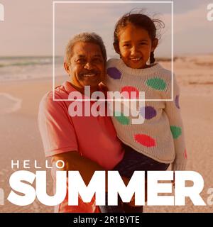 Kombination aus Hallo-Sommer-Text und birassisch lächelndem Großvater, der seine Enkelin am Strand trägt Stockfoto