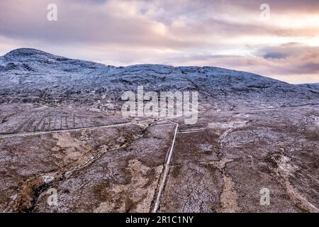 Der R251 neben dem schneebedeckten Berg Errigal, der höchste Berg in Donegal - Irland Stockfoto