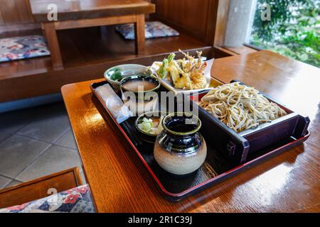 Zaru Soba ist ein gekühltes Nudelgericht, das mit einer Tauchsoße und Nori-Algen auf einem flachen Korb oder einem Teller serviert wird. Stockfoto