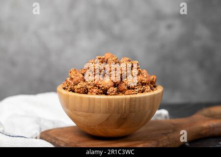 Honig mit Sesamnüssen. Sesamnüsse in einer Holzschüssel. Superfood, vegetarisches Speisenkonzept. Gesunde Snacks Stockfoto