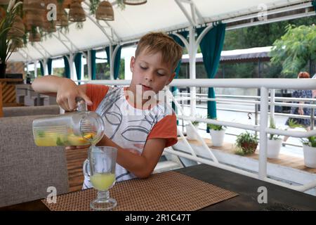 Ein Junge, der im Restaurant ein Glas mit Saft füllt Stockfoto