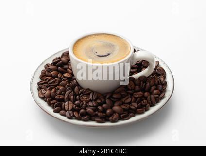 Espresso-Kaffee in einer kleinen Tasse und frische rohe Bohnen auf einer Untertasse auf Weiß. Stockfoto