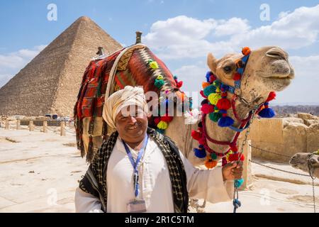 Porträt eines Mannes neben seinem Kamel und Blick auf die große Pyramide von Gizeh in Kairo, Ägypten Stockfoto