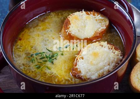 Eine klassische französische Zwiebelsuppe mit gräulichem Käse und getoastetem Baguette in einer Schüssel Stockfoto