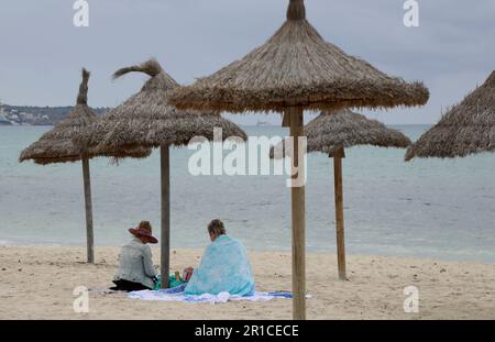 Palma, Spanien. 11. Mai 2023. Zwei Frauen, die am Strand unter einem Sonnenschirm sitzen. Die Playa de Palma am Ballermann auf Mallorca hat die „blaue Flagge“ und damit den Status als Strand von ausgezeichneter Qualität verloren. (Zu dpa 'Ballermann Beach verliert 'blaue Flagge' für exzellente Qualität') Kredit: Clara Margais/dpa/Alamy Live News Stockfoto