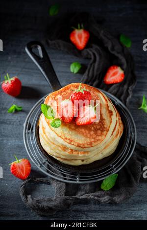 Leckere und frische amerikanische Pfannkuchen mit Erdbeeren und Zucker. Pfannkuchen mit Puderzucker und Erdbeeren. Stockfoto