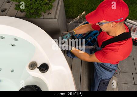 Wannen-Whirlpool für Haushalte, saisonale Wartung, durchgeführt von einem professionellen, kaukasischen Spa-Techniker in seinem 40s. Stockfoto