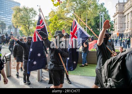 Neonazis-Demonstranten mit Flaggen salutieren, da sie während der Demonstration das Gebiet verlassen sollen. Ein Tag politischer Spannungen und Zusammenstöße entfaltete sich in Melbourne als rechtsextreme Gruppe einer Neonazi-Gruppe, die eine Anti-Einwanderungs-Kundgebung im staatsparlament veranstaltete, und traf auf heftigen Widerstand von linksgerichteten antifaschistischen Gegenprotestierenden. Die Aufruhr-Polizei wurde eingesetzt, als es zwischen den beiden Gruppen zu Schlägereien kam, mit Pfefferspray und Pferden, um die Menge zu kontrollieren. Protestsignale, die Inklusivität, Vielfalt und soziale Gerechtigkeit fordern, wurden in einer Demonstration der Einheit gegen Hassreden und Diskriminierung hoch gehalten. Die Überschneidung Stockfoto