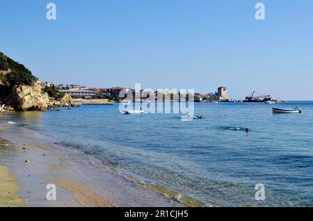 Ouranoupoli, Chalkidiki, Griechenland - 29. September 2011: Unidentifizierte Menschen, Strand und mittelalterlicher Prosphorios-Turm im Dorf auf der Halbinsel Athos Stockfoto