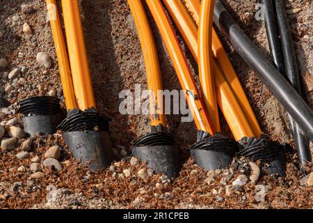 Glasfaserkabel und Fernwärme werden im orangefarbenen Straßenkabel verlegt Stockfoto