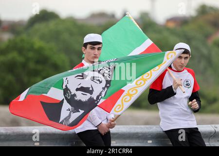 Urus Martan, Russland. 12. Mai 2023. RUSSLAND, REPUBLIK TSCHETSCHENIEN - 12. MAI 2023: Männer halten die Flagge bei der Enthüllung des Wasserkraftwerks Argun. Der Start des Komplexes, der die Bewässerungsgebiete Urus-Martan und Shalinsky versorgt, wird gute Bedingungen für die Entwicklung des agroindustriellen Komplexes der Region schaffen. Yelena Afonina/TASS/ABACAPRESS.COM Kredit: Abaca Press/Alamy Live News Stockfoto